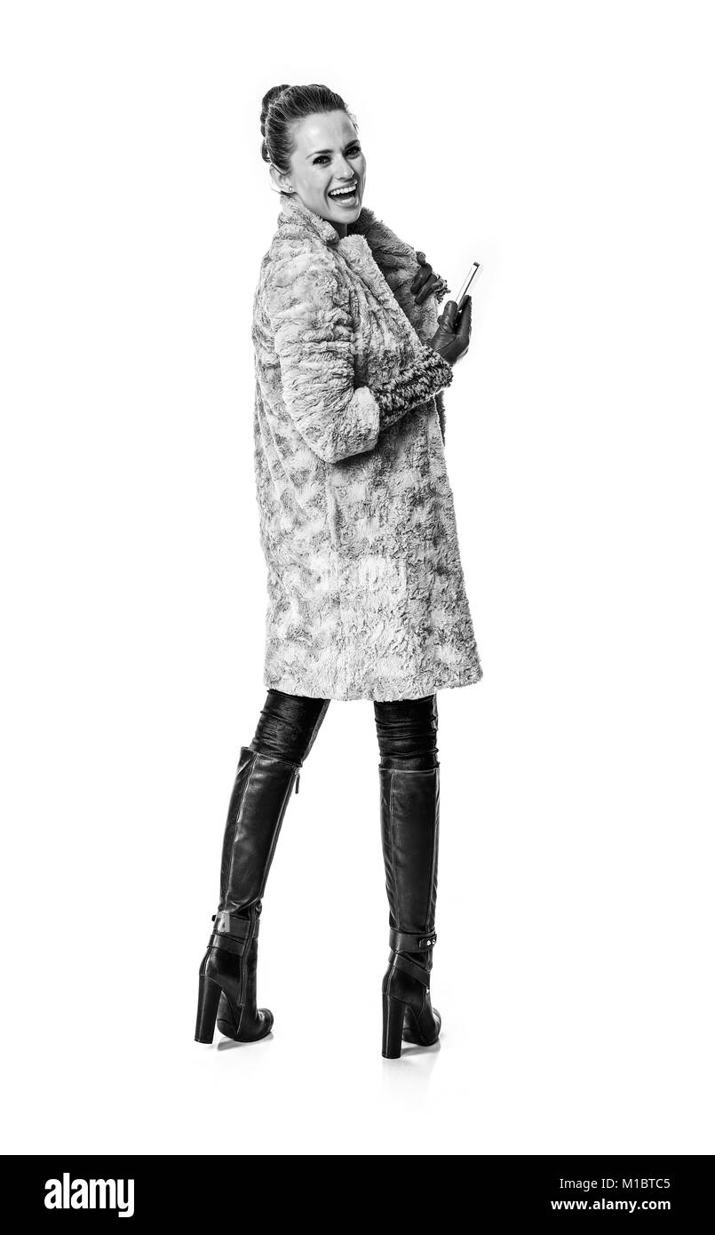 Cose d'inverno. A piena lunghezza Ritratto di felice moda giovane-monger in cappotto invernale isolato su bianco con lo smartphone Foto Stock