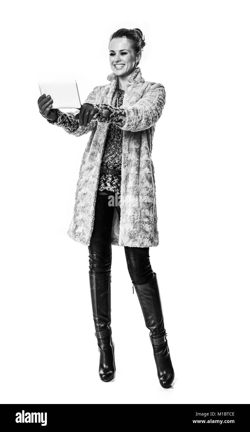 Cose d'inverno. A piena lunghezza Ritratto di sorridere alla moda-monger in cappotto invernale isolato su bianco utilizzando un tablet PC Foto Stock