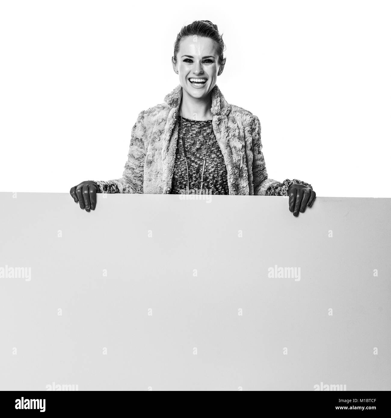 Cose d'inverno. A piena lunghezza Ritratto di sorridente donna elegante in inverno coat isolato su sfondo bianco che mostra la scheda vuota Foto Stock
