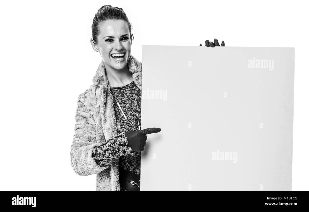Cose d'inverno. A piena lunghezza Ritratto di felice alla moda donna in cappotto invernale isolato su bianco rivolto a blank board Foto Stock
