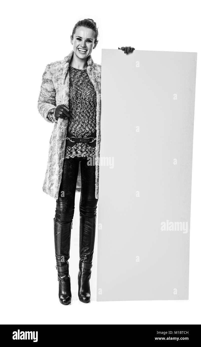 Cose d'inverno. A piena lunghezza Ritratto di felice alla moda donna in cappotto invernale isolato su bianco che mostra la scheda vuota Foto Stock