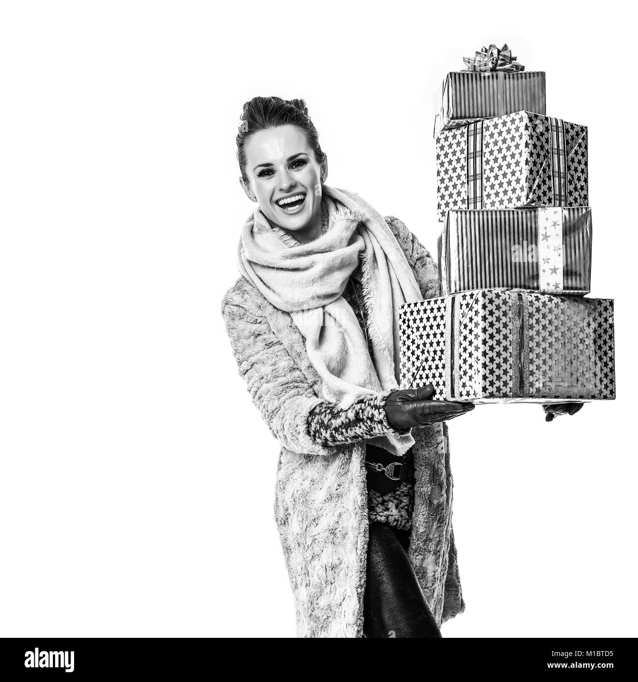 Cose d'inverno. A piena lunghezza Ritratto di felice giovane donna in cappotto invernale isolato su sfondo bianco con la pila di Natale le caselle presenti a piedi Foto Stock