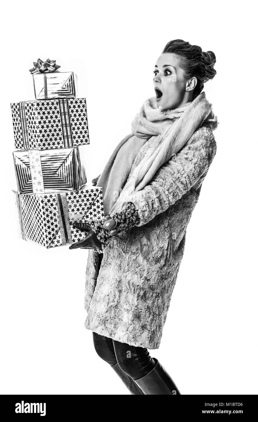 In inverno le cose. sorpreso donna moderna in cappotto invernale isolato su sfondo bianco con la pila di regalo di Natale scatole Foto Stock