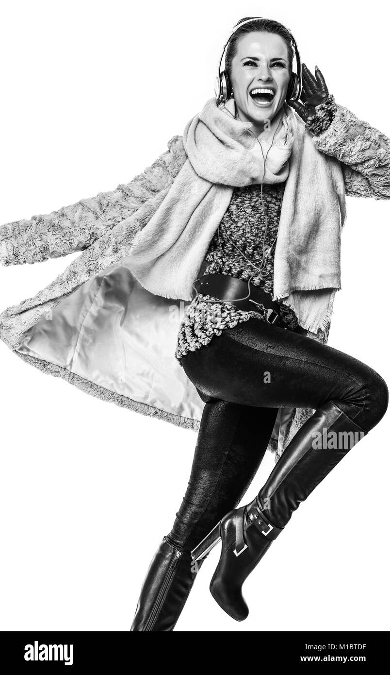 Cose d'inverno. A piena lunghezza Ritratto di felice elegante fashion-monger in cappotto invernale isolato su sfondo bianco con le cuffie per ascoltare la musica Foto Stock