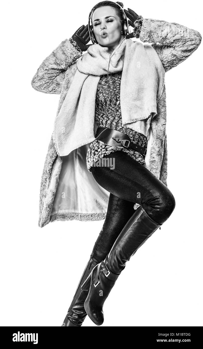 Cose d'inverno. A piena lunghezza Ritratto di sorridere elegante fashion-monger in cappotto invernale isolato su bianco con le cuffie per ascoltare la musica e danc Foto Stock