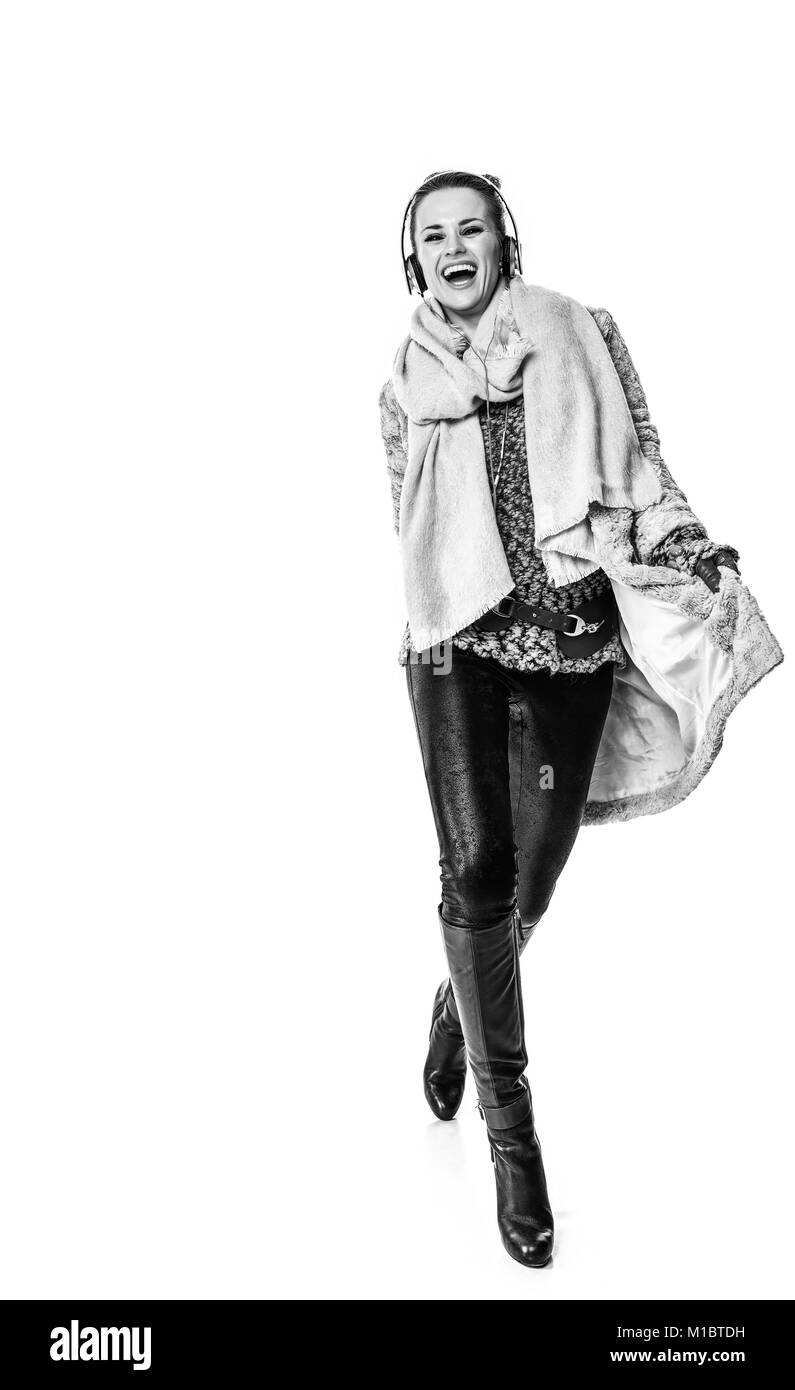 Cose d'inverno. A piena lunghezza Ritratto di felice alla moda-monger in cappotto invernale isolato su sfondo bianco con le cuffie per ascoltare la musica Foto Stock