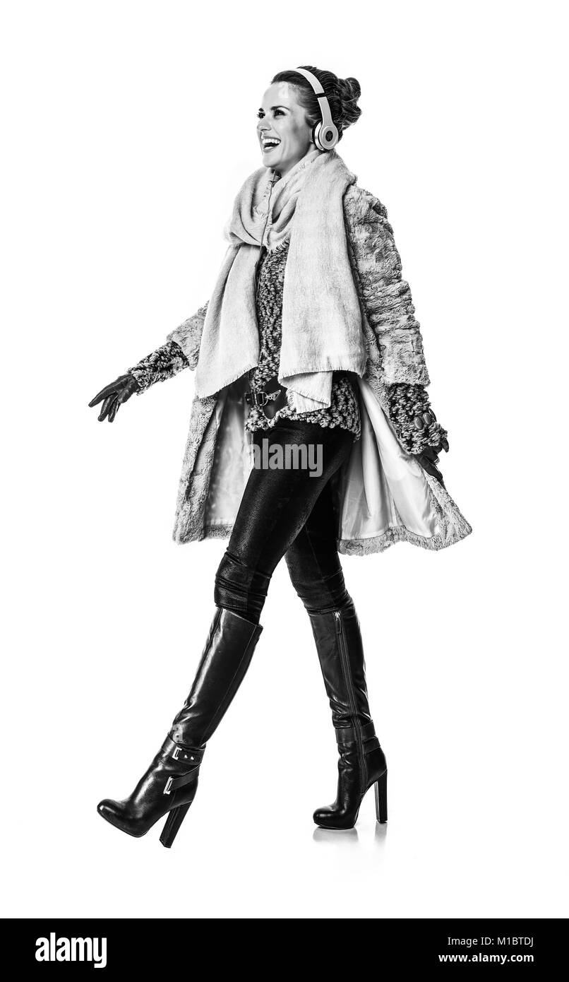 Cose d'inverno. A piena lunghezza Ritratto di giovane sorridente fashion-monger in cappotto invernale isolato su sfondo bianco con le cuffie per ascoltare la musica Foto Stock