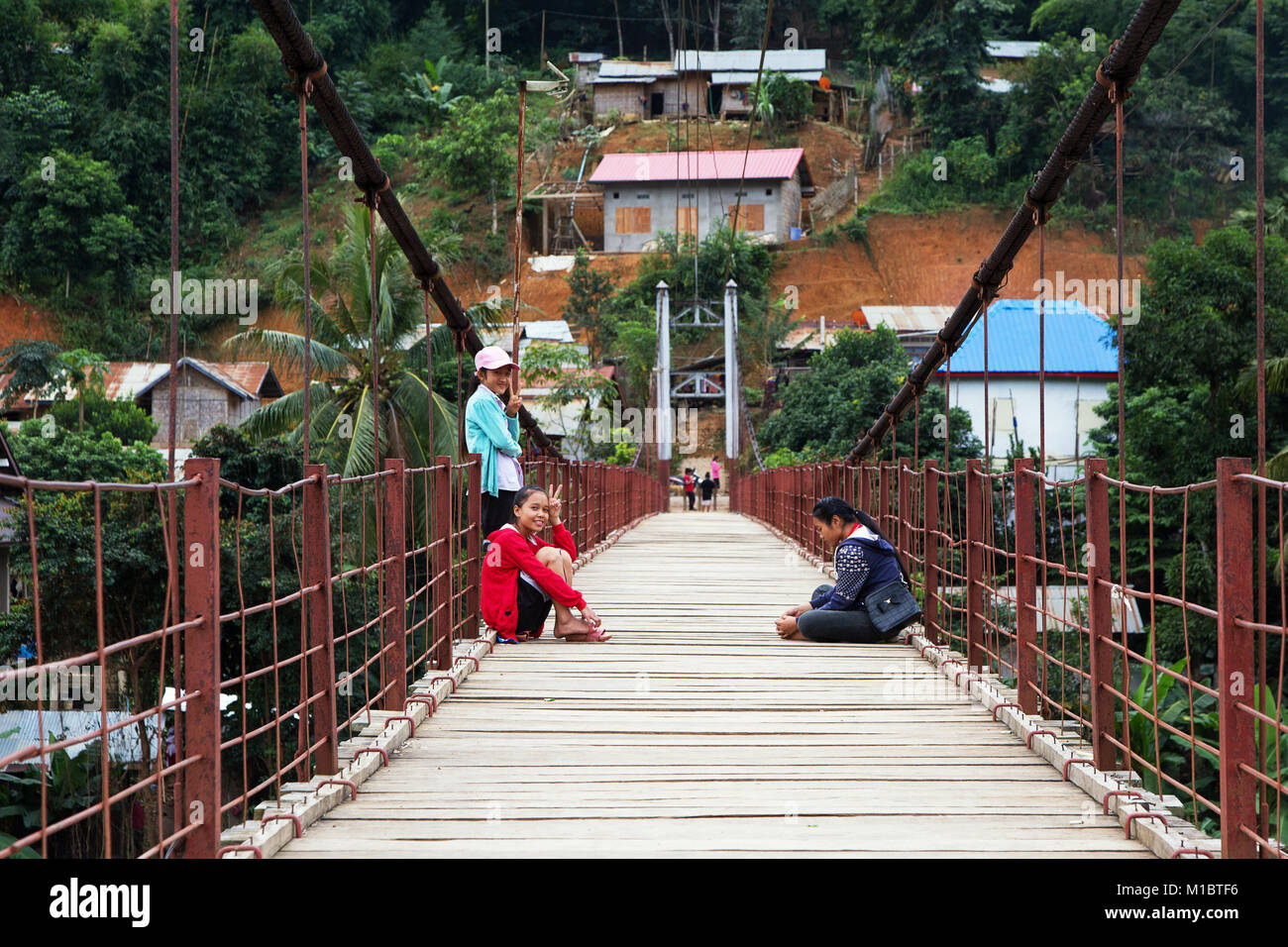Giovani ragazze laotiane seduti su un ponte di sospensione in Muang Khoua, Nord del Laos, Asia Foto Stock