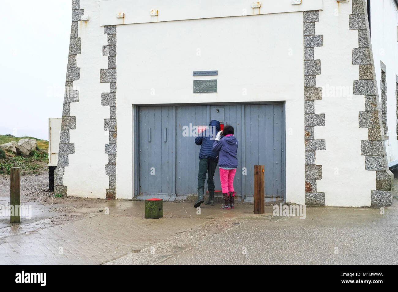 Newquay inverno - Due escursionisti persone cercano nella storica Vecchia Stazione di salvataggio su Towan testa in Newquay Cornwall. Foto Stock