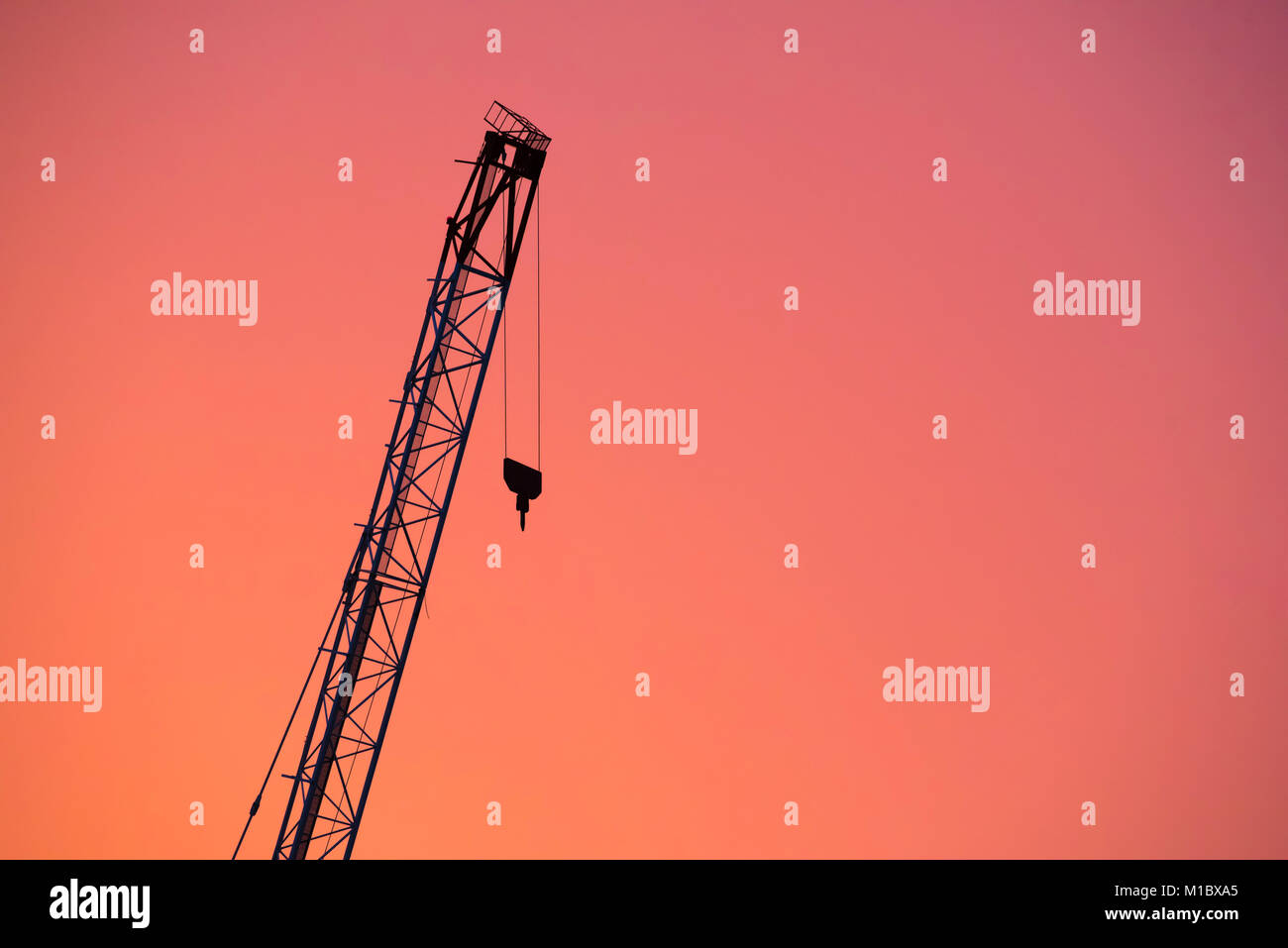 Costruzione di un braccio di gru su un sito di costruzione stagliano contro un arancione tramonto di Sydney, Australia Foto Stock