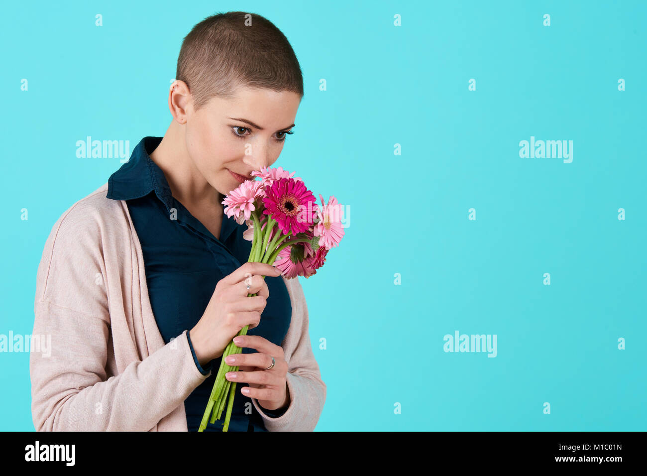 Attraente giovane donna con capelli corti profumati bouquet di pink gerbera margherite. Buon compleanno concetto. Foto Stock