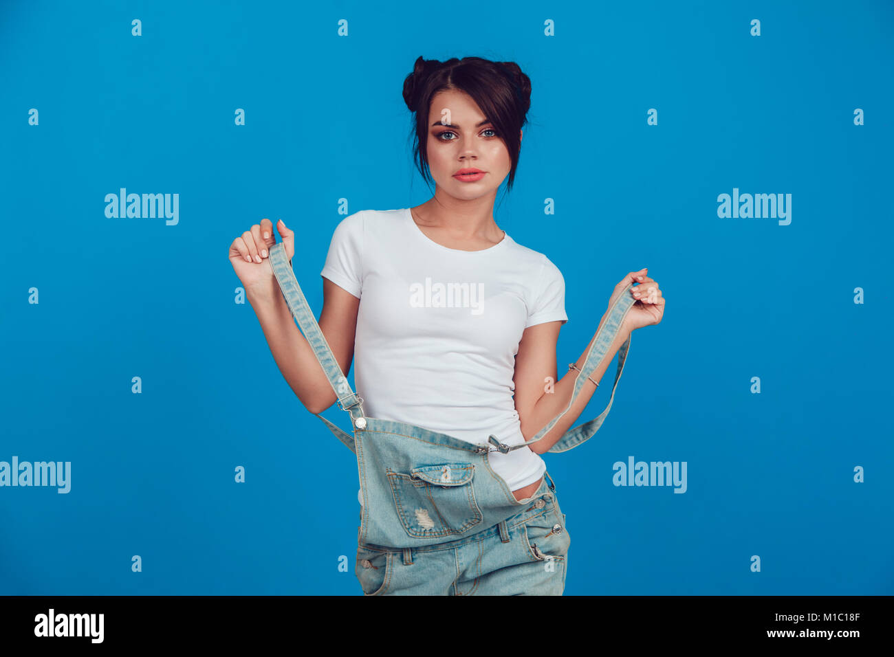 Donna attraente in una t-shirt bianca sorge su uno sfondo blu. Mock-up. Foto Stock