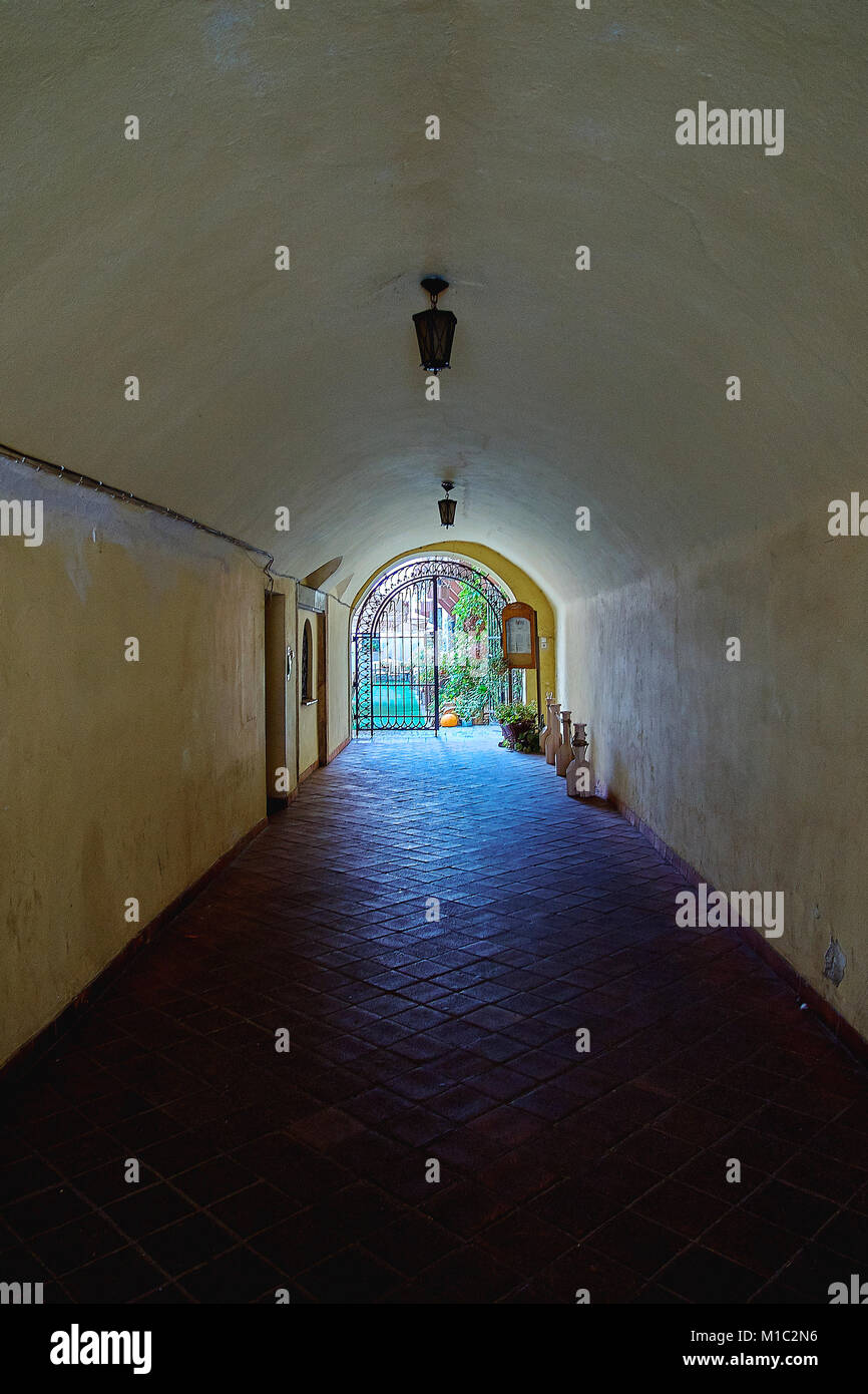 Un antico borgo medievale tunnel di pietra sotto la parete di fortezza con un giardino e la luce alla fine Foto Stock