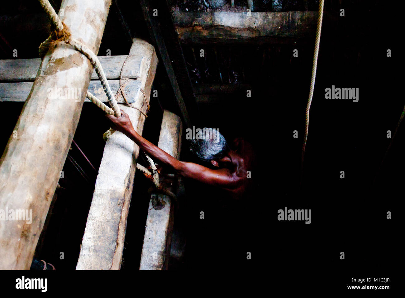 Madampagama, Sri Lanka - Dicembre 2015 - Un uomo vecchio scendendo da un tombino per la gioielleria mining, Asia Foto Stock