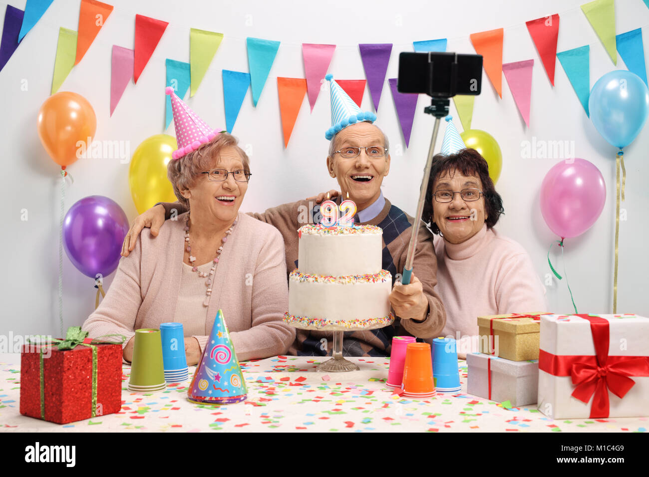 Happy seniors prendendo un selfie con un bastone ad una festa di compleanno Foto Stock