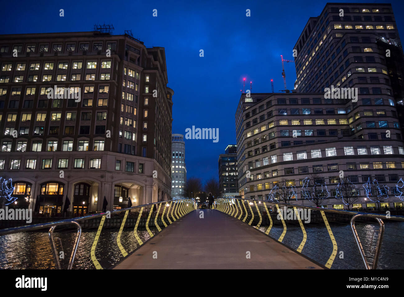 Ponte su acqua a Canary Wharf distretto finanziario di notte, Docklands, Londra, Inghilterra, Regno Unito Foto Stock