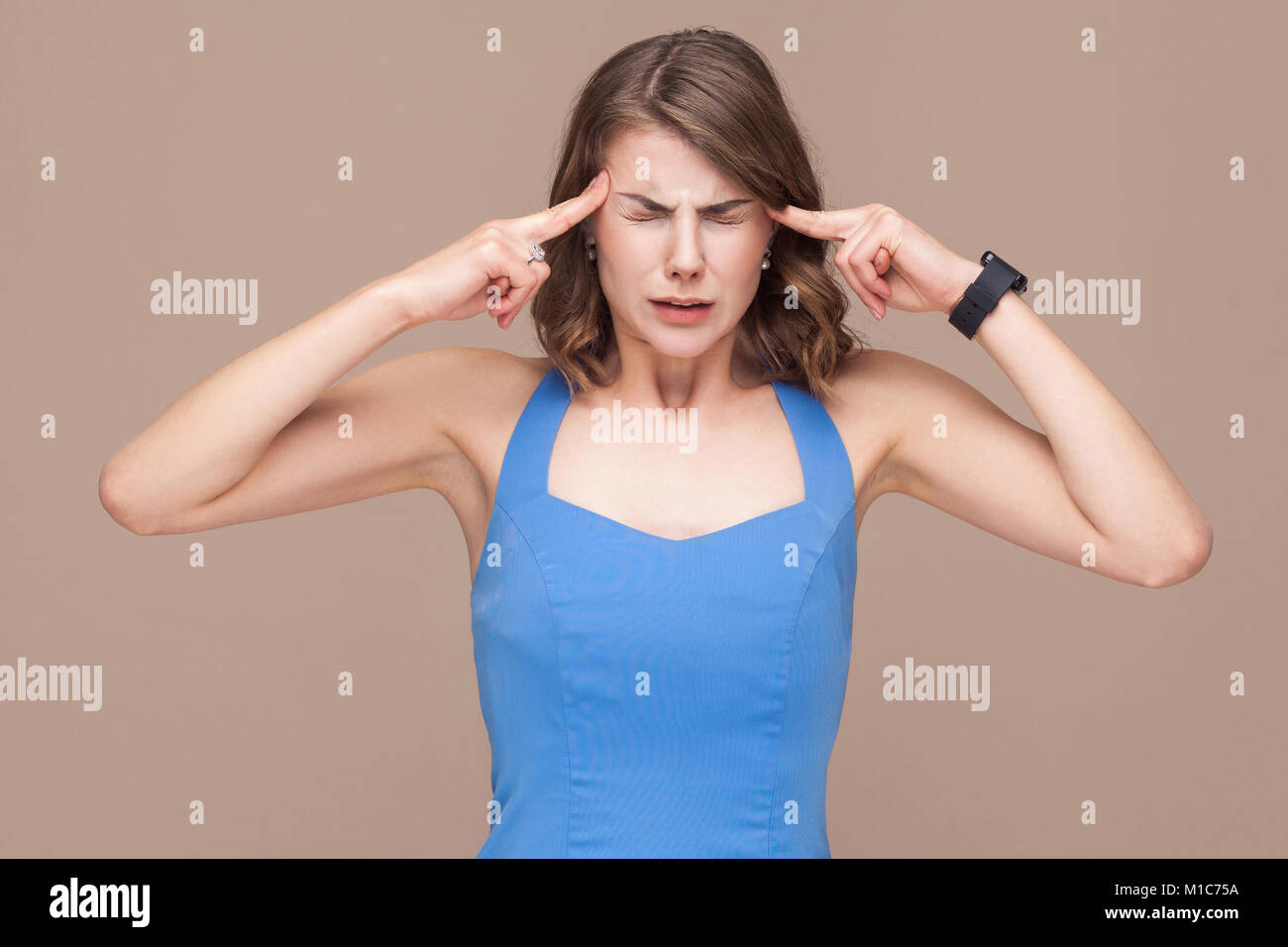 Business donna hanno mal di testa o emicrania. Studio shot, luce sfondo marrone Foto Stock