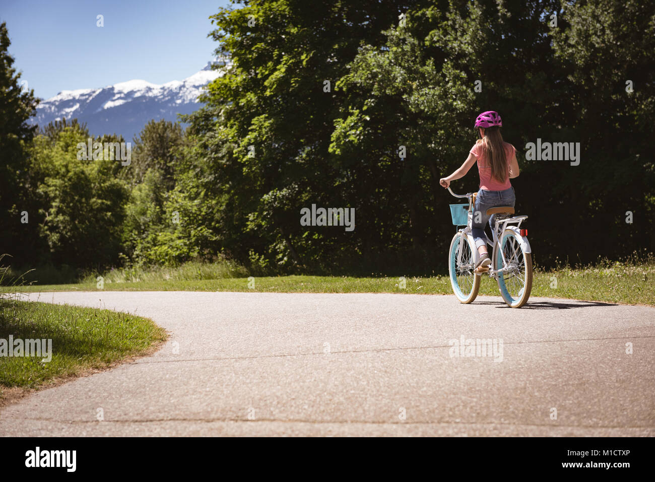 Ragazza che indossa il casco di sicurezza equitazione bicicletta su strada in una giornata di sole Foto Stock