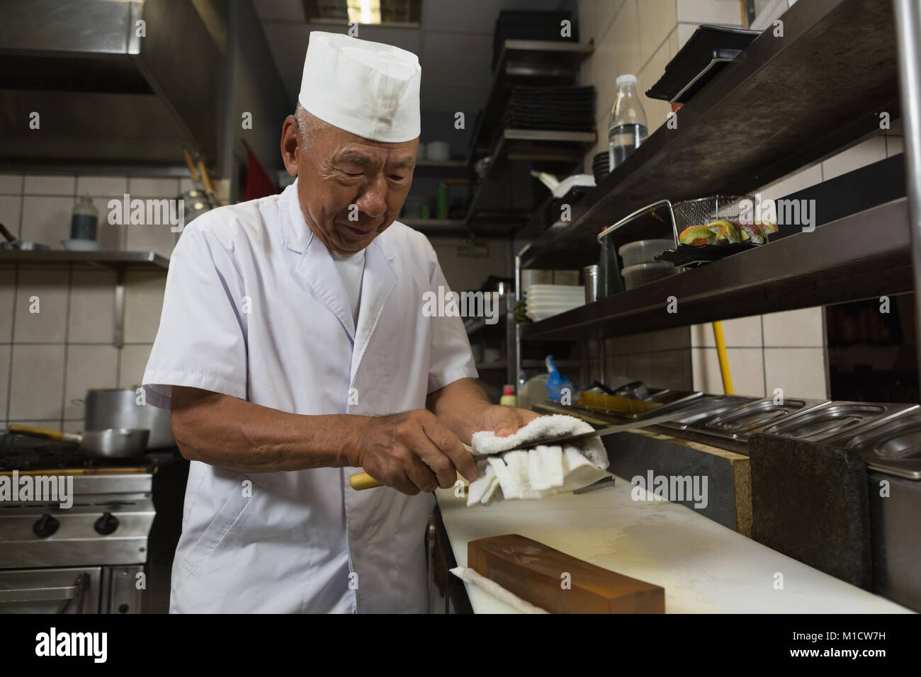 Senior chef tenendo il coltello in cucina Foto Stock