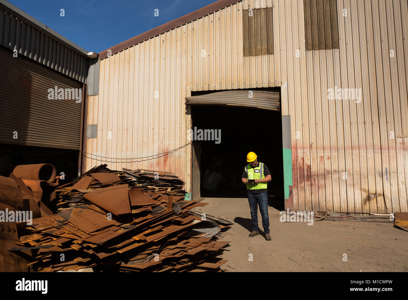 Lavoratore con tavoletta digitale a scrapyard Foto Stock
