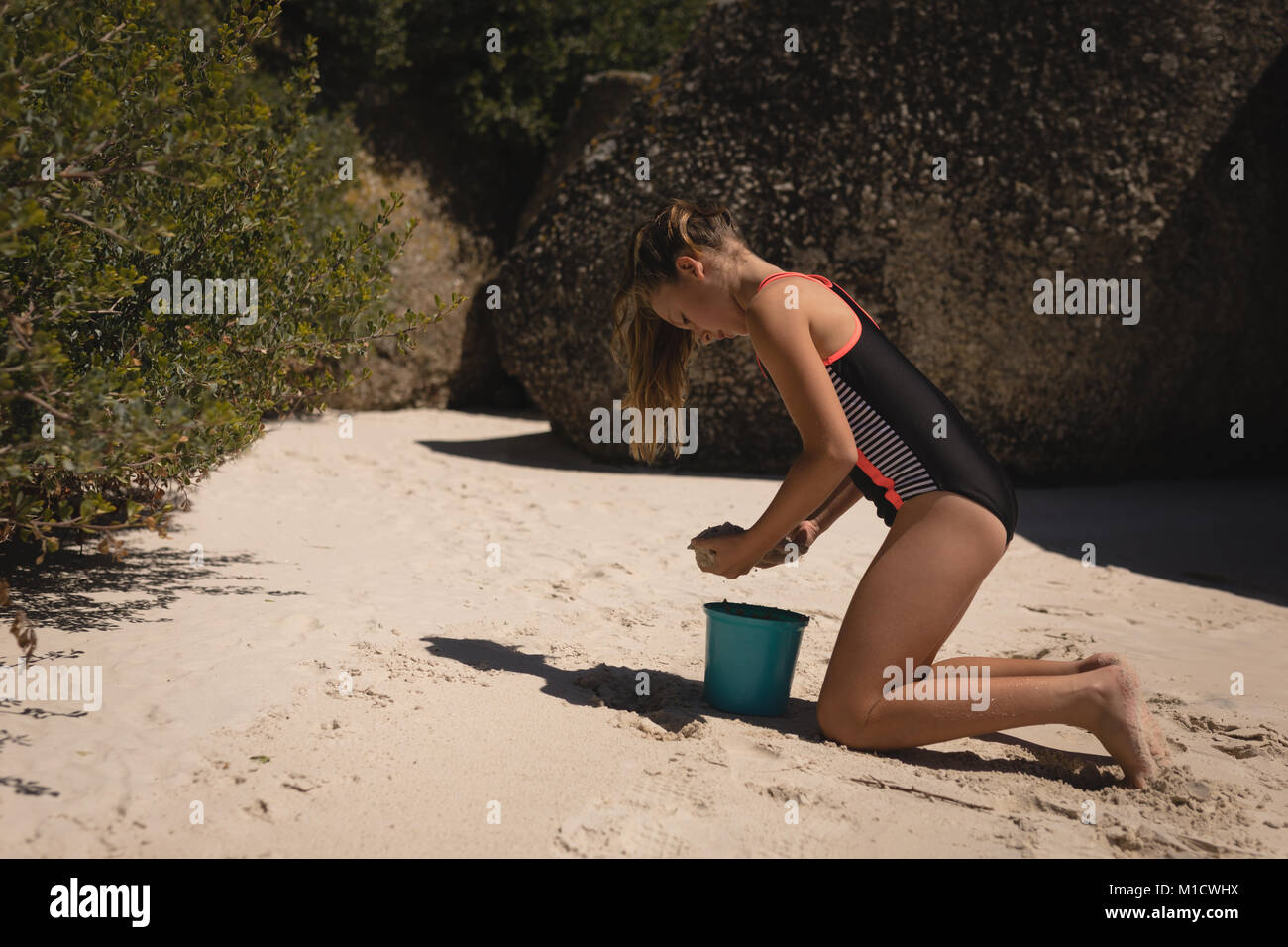 Ragazza che gioca con la sabbia in spiaggia Foto Stock
