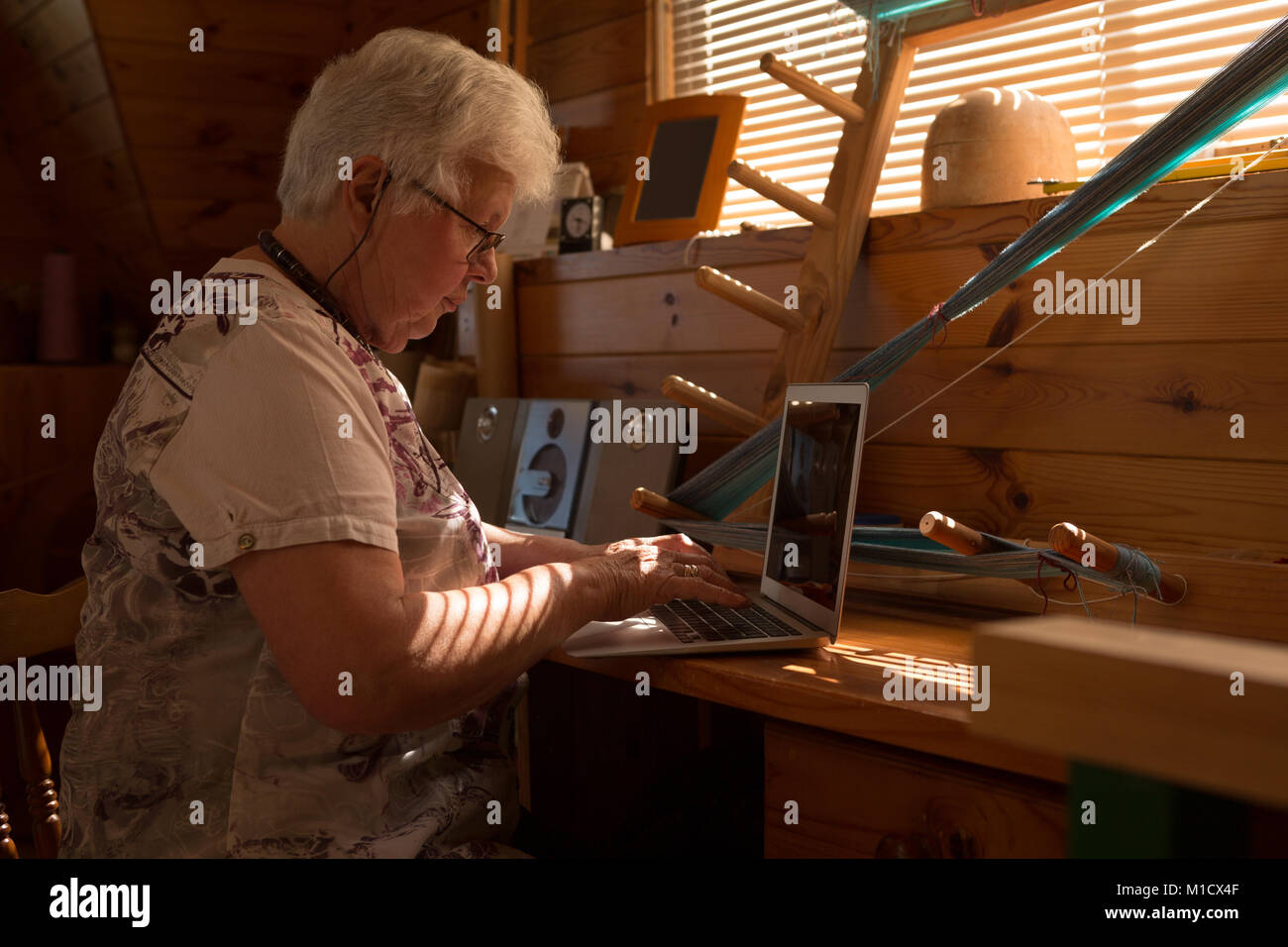 Senior donna utilizzando laptop alla scrivania Foto Stock