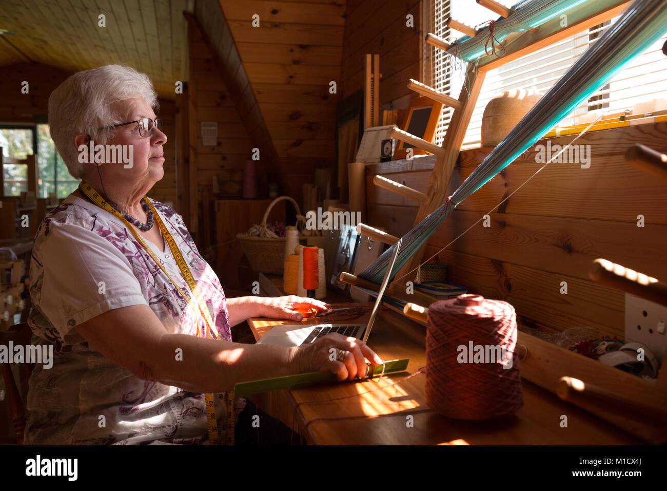 Senior donna seta tessitura al shop Foto Stock