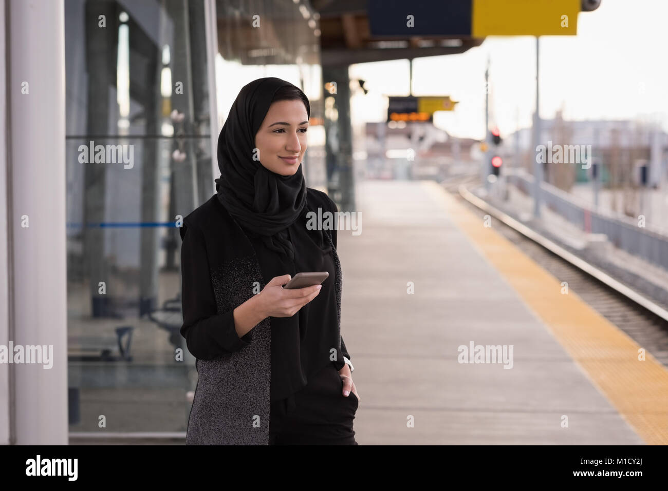 Donna in hijab utilizzando il telefono cellulare Foto Stock