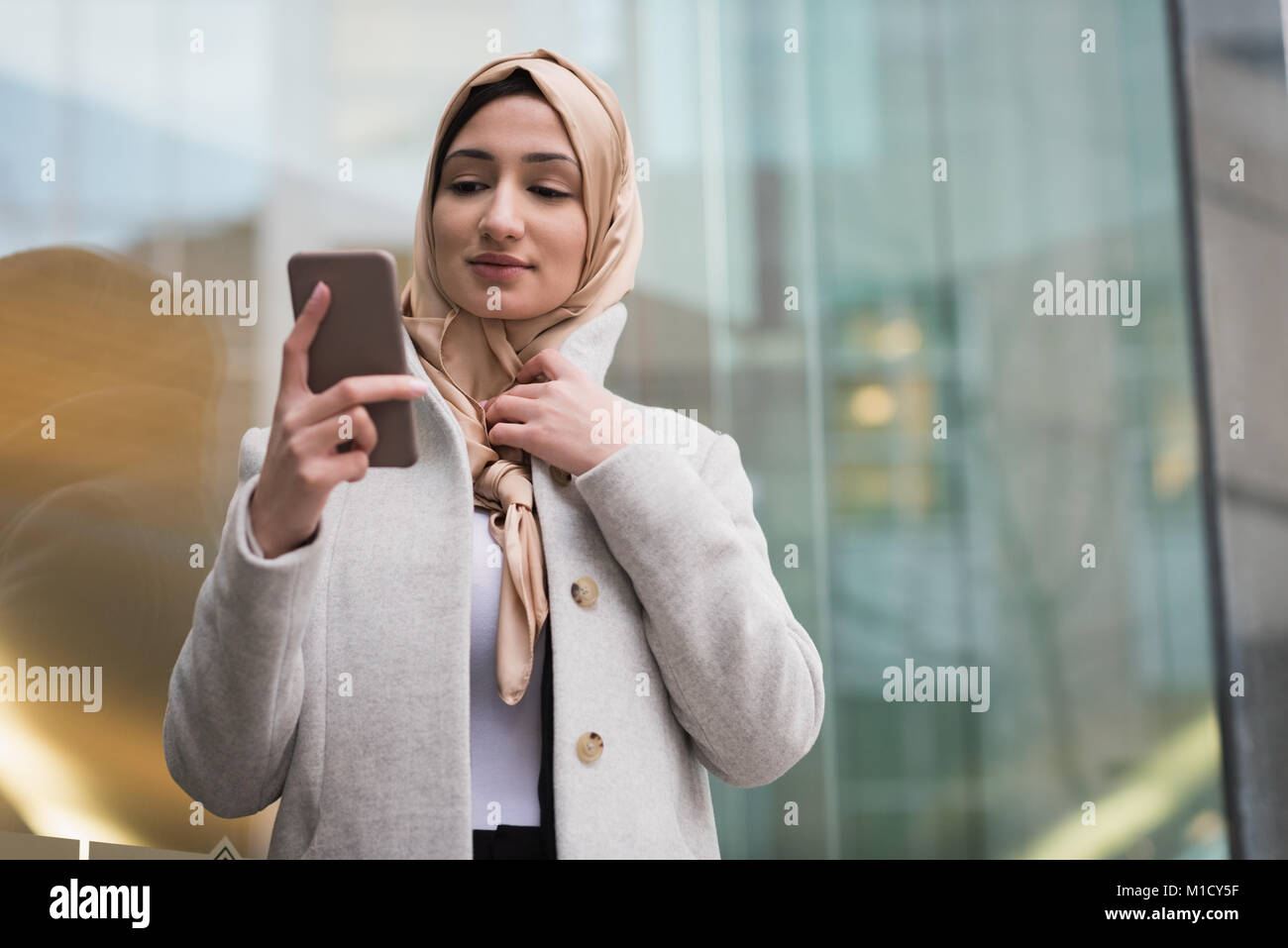 Donna in hijab utilizzando il telefono cellulare Foto Stock