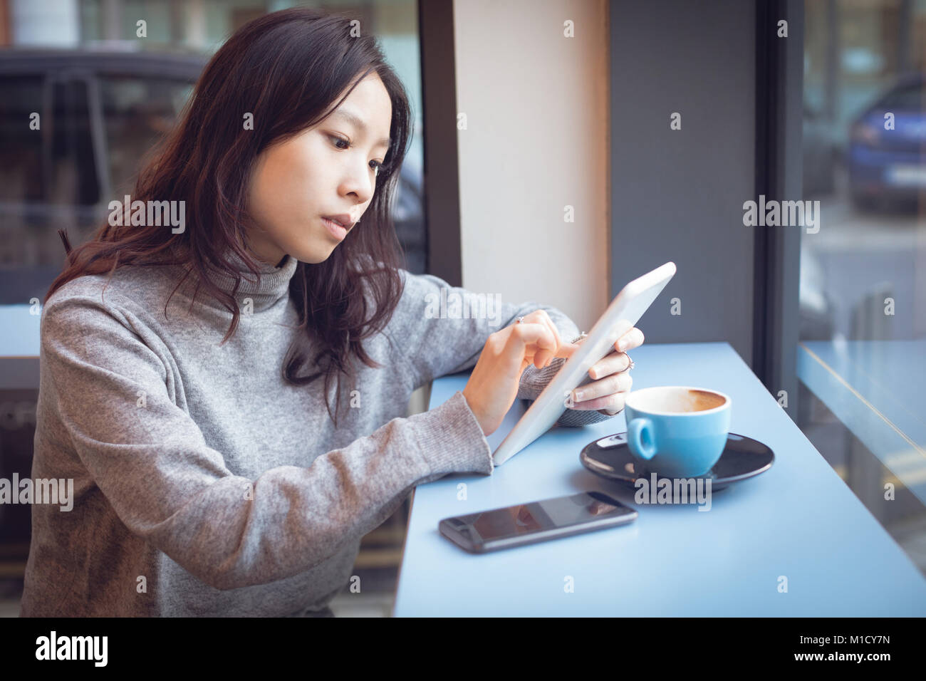 Bella donna utilizzando digitale compressa mentre un caffè Foto Stock