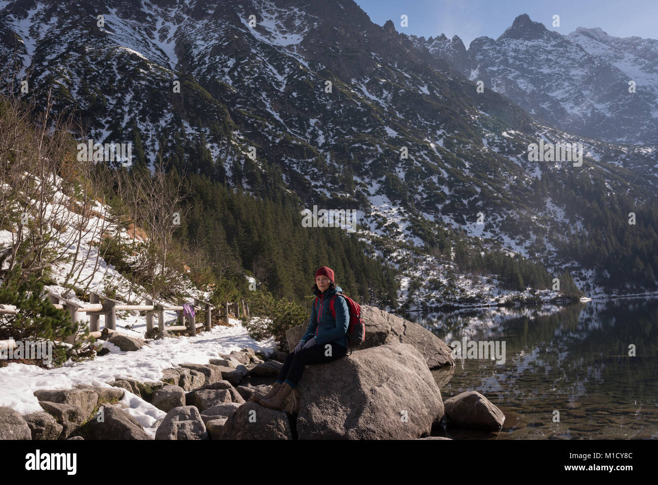 Escursionista femmina seduto sulla roccia a Lakeside Foto Stock