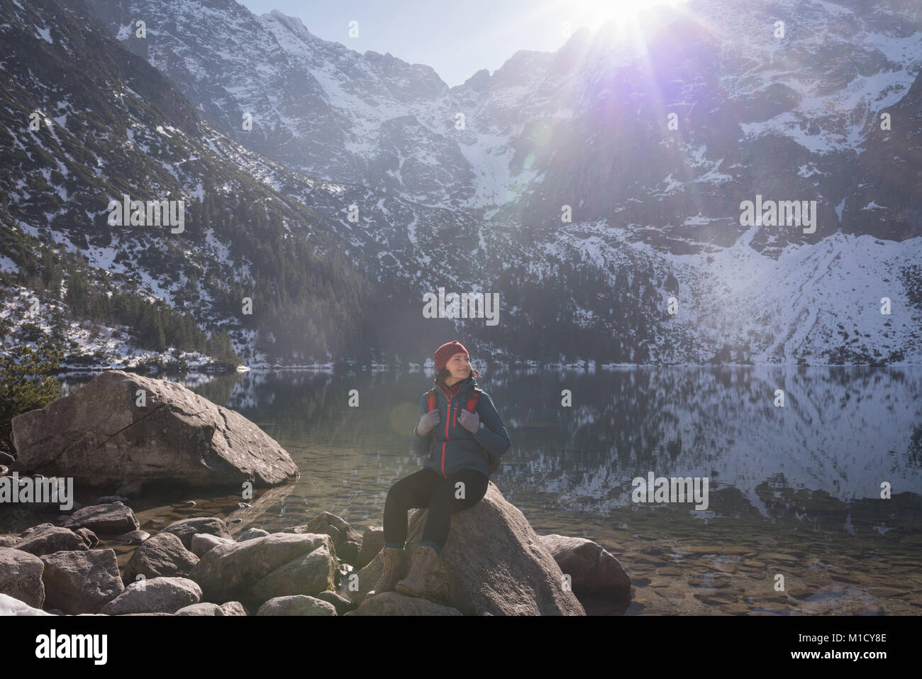 Escursionista femmina seduto sulla roccia a Lakeside Foto Stock