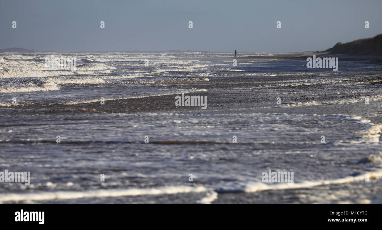 Un uomo solo su una spiaggia di fronte al mare. Foto Stock