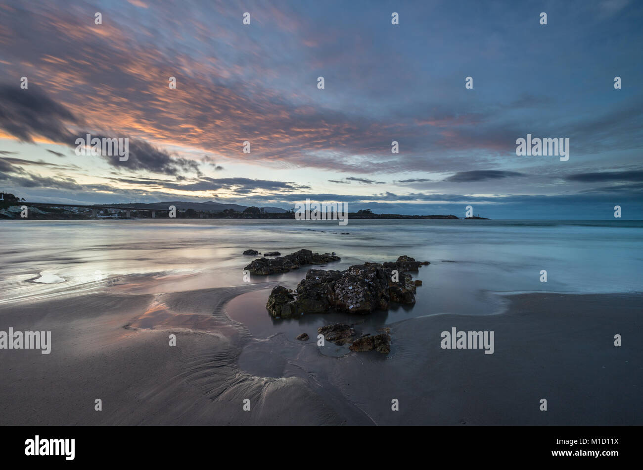 Un tramonto spettacolare sulla spiaggia di Arnao, Asturias, fotografando i diversi colori, forme e texture delle nuvole, riflessa nella sabbia fine Foto Stock