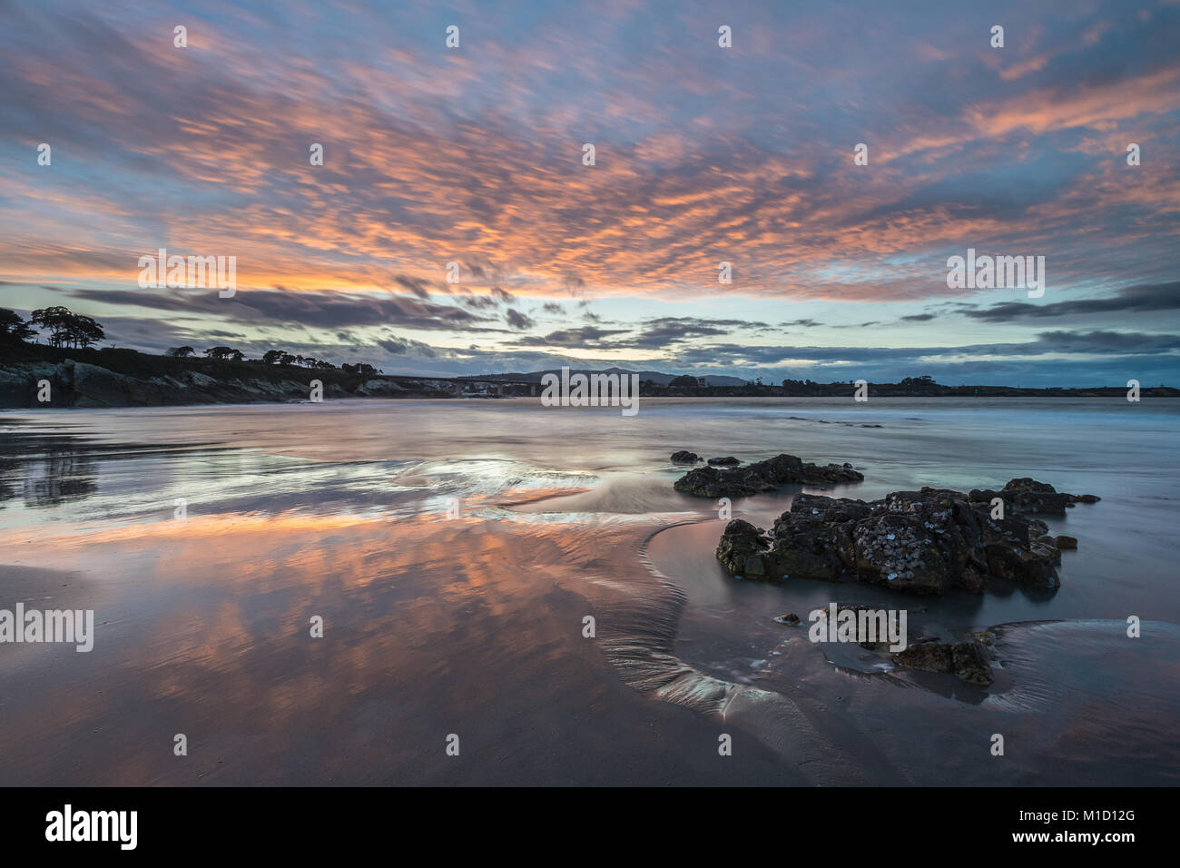 Un tramonto spettacolare sulla spiaggia di Arnao, Asturias, fotografando i diversi colori, forme e texture delle nuvole, riflessa nella sabbia fine Foto Stock