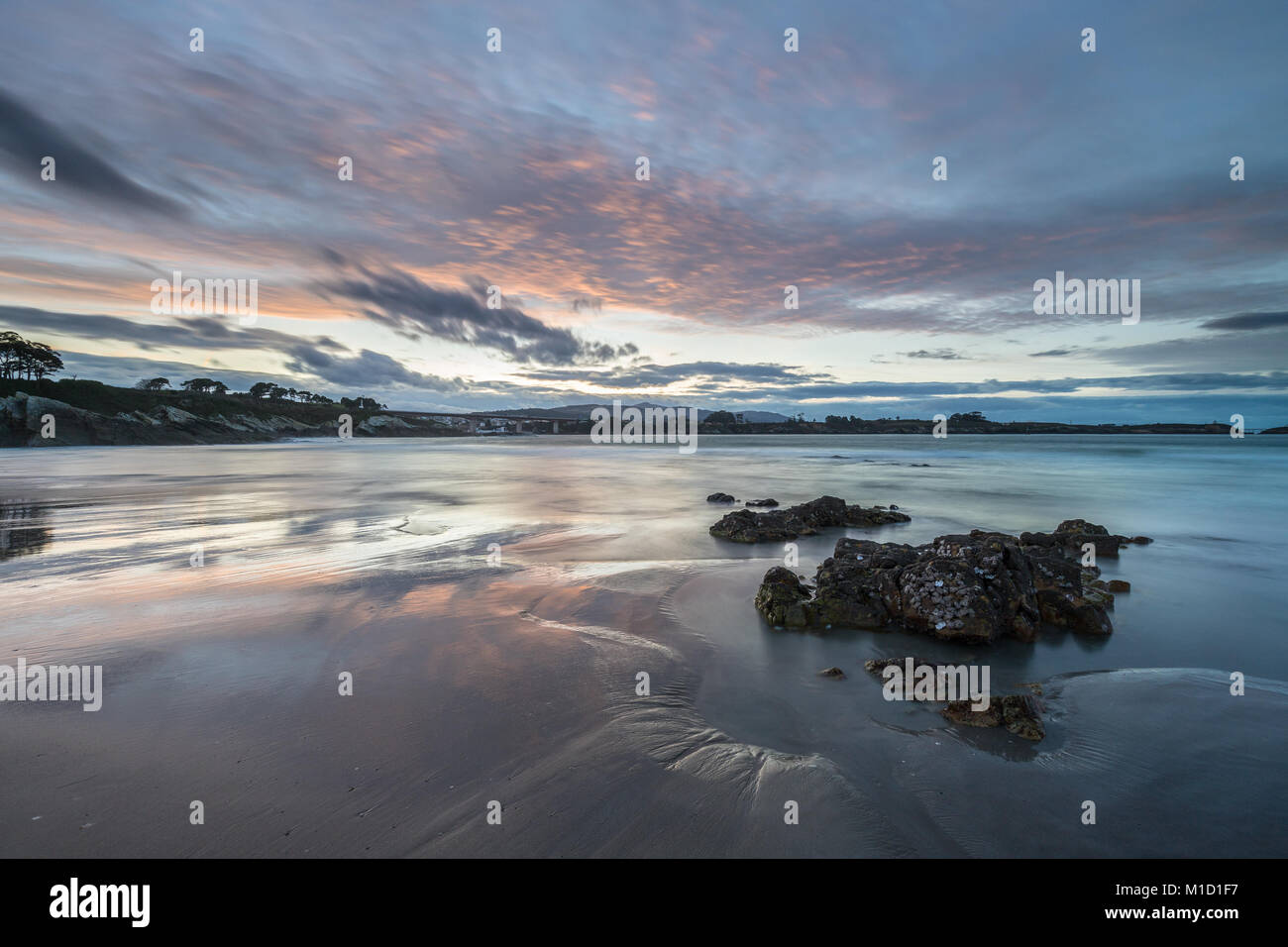 Un tramonto spettacolare sulla spiaggia di Arnao, Asturias, fotografando i diversi colori, forme e texture delle nuvole, riflessa nella sabbia fine.. Foto Stock