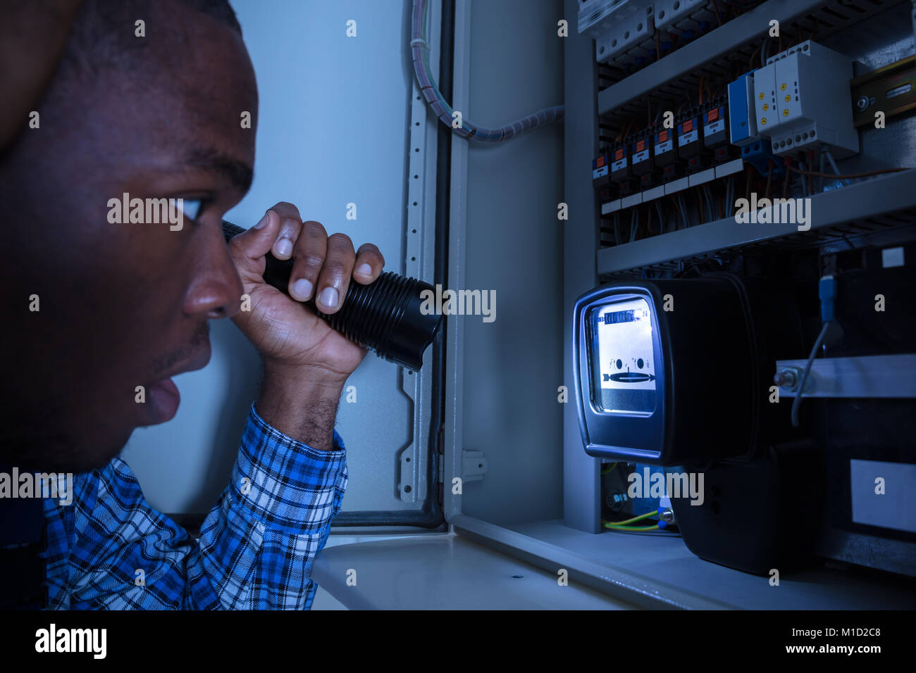Close-up di un elettricista in esame di un contatore di energia elettrica con una torcia Foto Stock