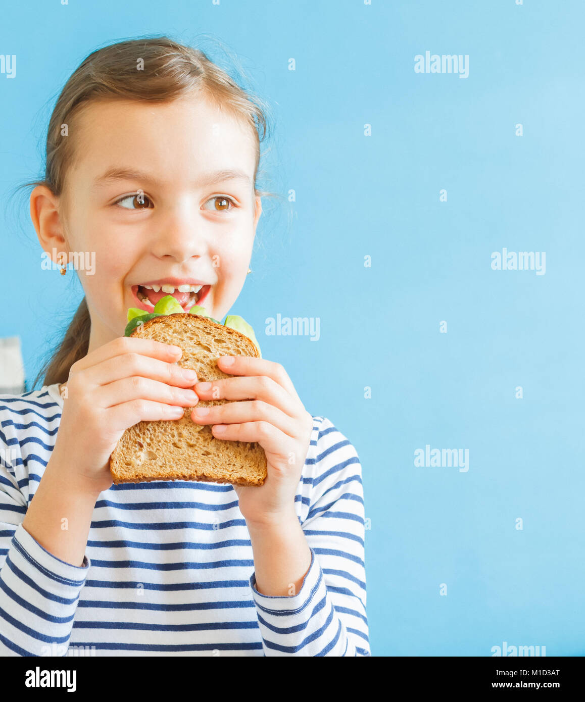 Ragazza sorridente mangiar sano in sandwich con insalata e avocado Foto Stock