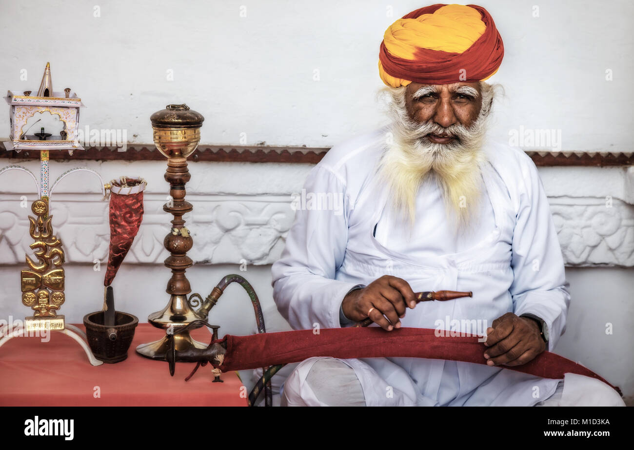 Uomo più anziano in tradizionale Rajasthani e colorato turbante di fumare un narghilè a Forte Mehrangarh. Foto Stock