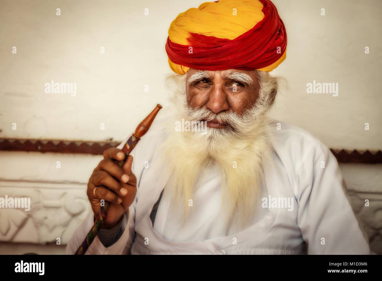 Uomo più anziano in tradizionale Rajasthani e colorato turbante di fumare un narghilè a Forte Mehrangarh. Foto Stock