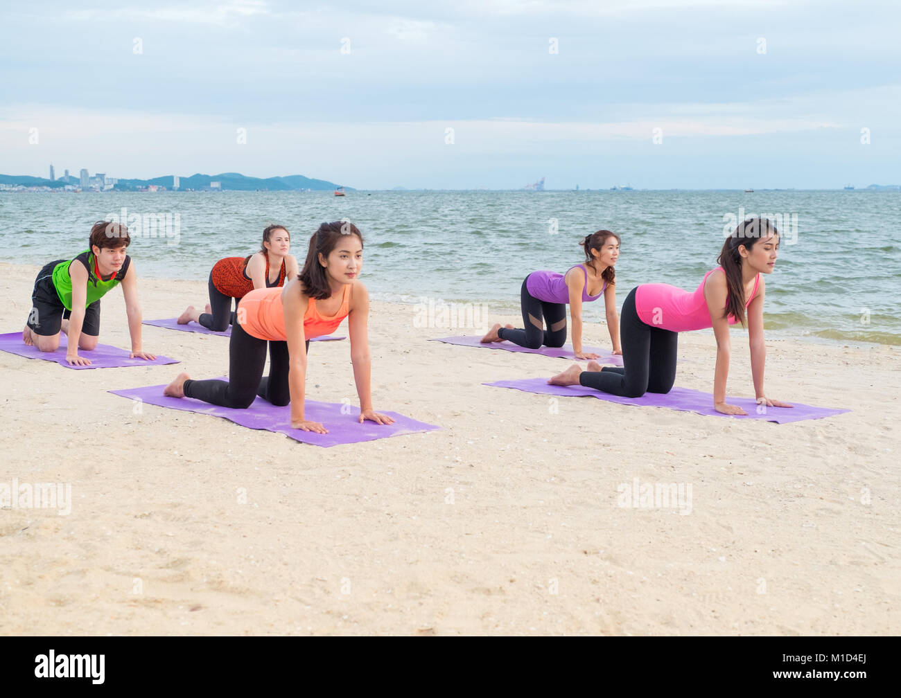 Classe di yoga in mare spiaggia di tramonto ,Gruppo di persone facendo cat pone con vongole emozione relax in spiaggia,Meditazione pongono,di benessere e salute balan Foto Stock