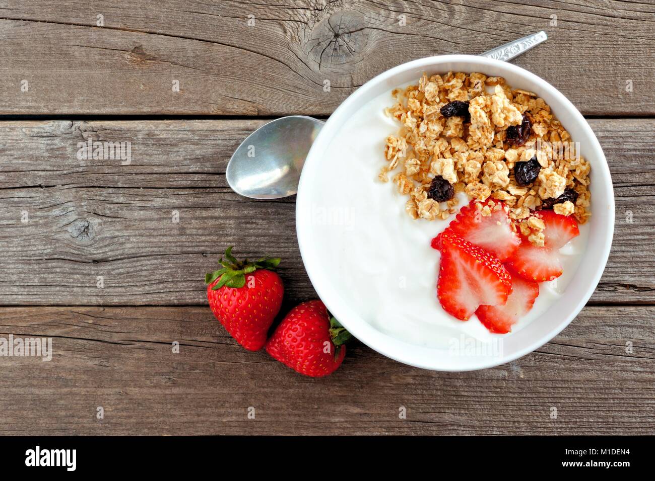 Ciotola di yogurt con fragole e muesli oltre un legno rustico sfondo. Lay piatto. Foto Stock