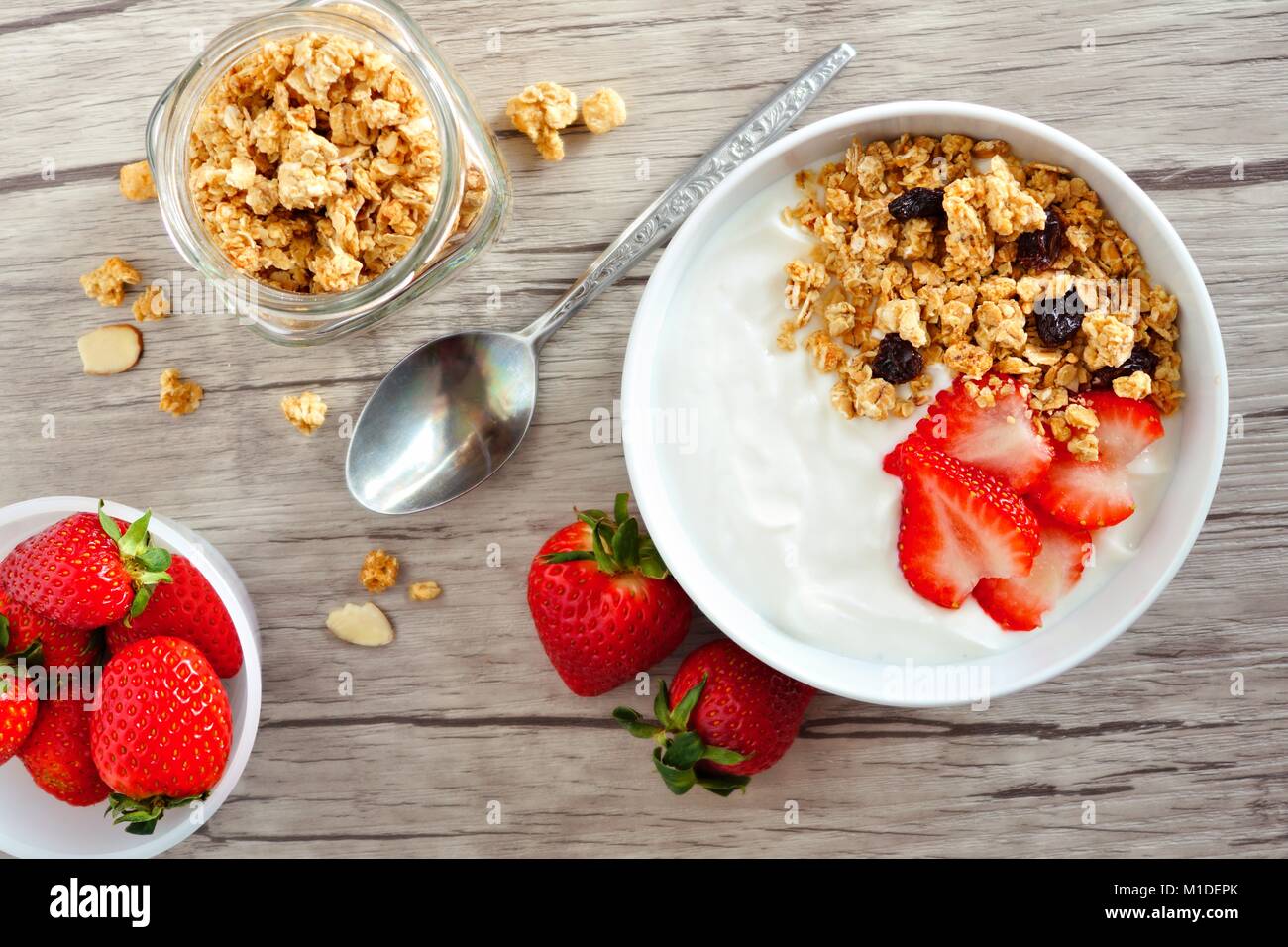 Yogurt con fragole e muesli. Tabella scena su un sfondo di legno. Foto Stock