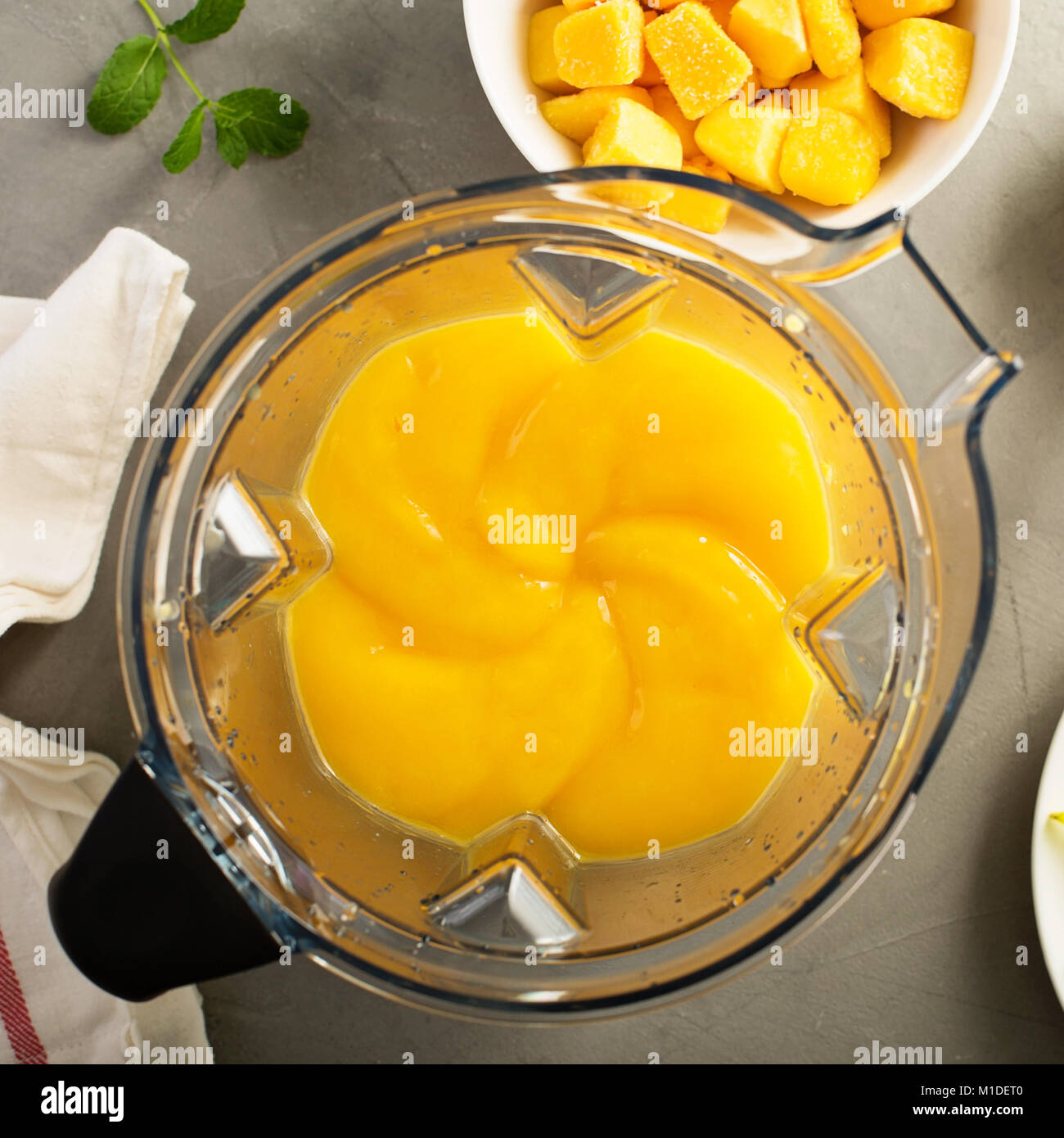 Rendendo smoothie con mango congelato Foto Stock