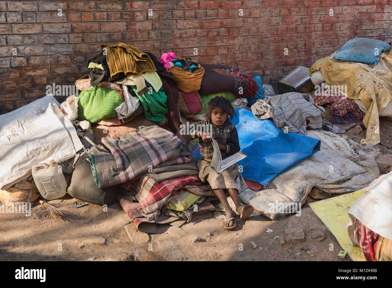 Senzatetto ragazzo lettura, Bikaner, Rajasthan, India Foto Stock