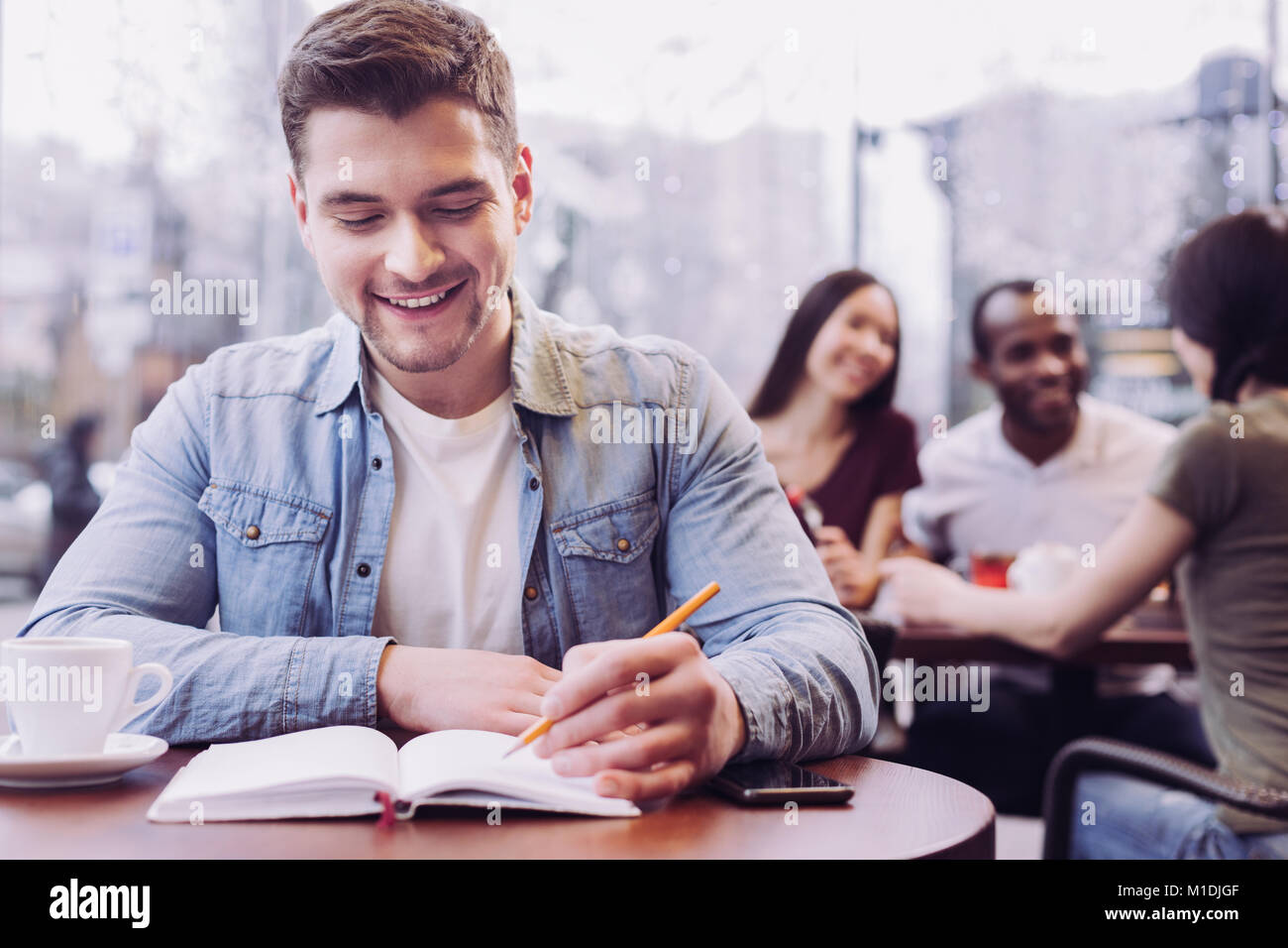 Allegro studente maschio a scrivere i compiti Foto Stock