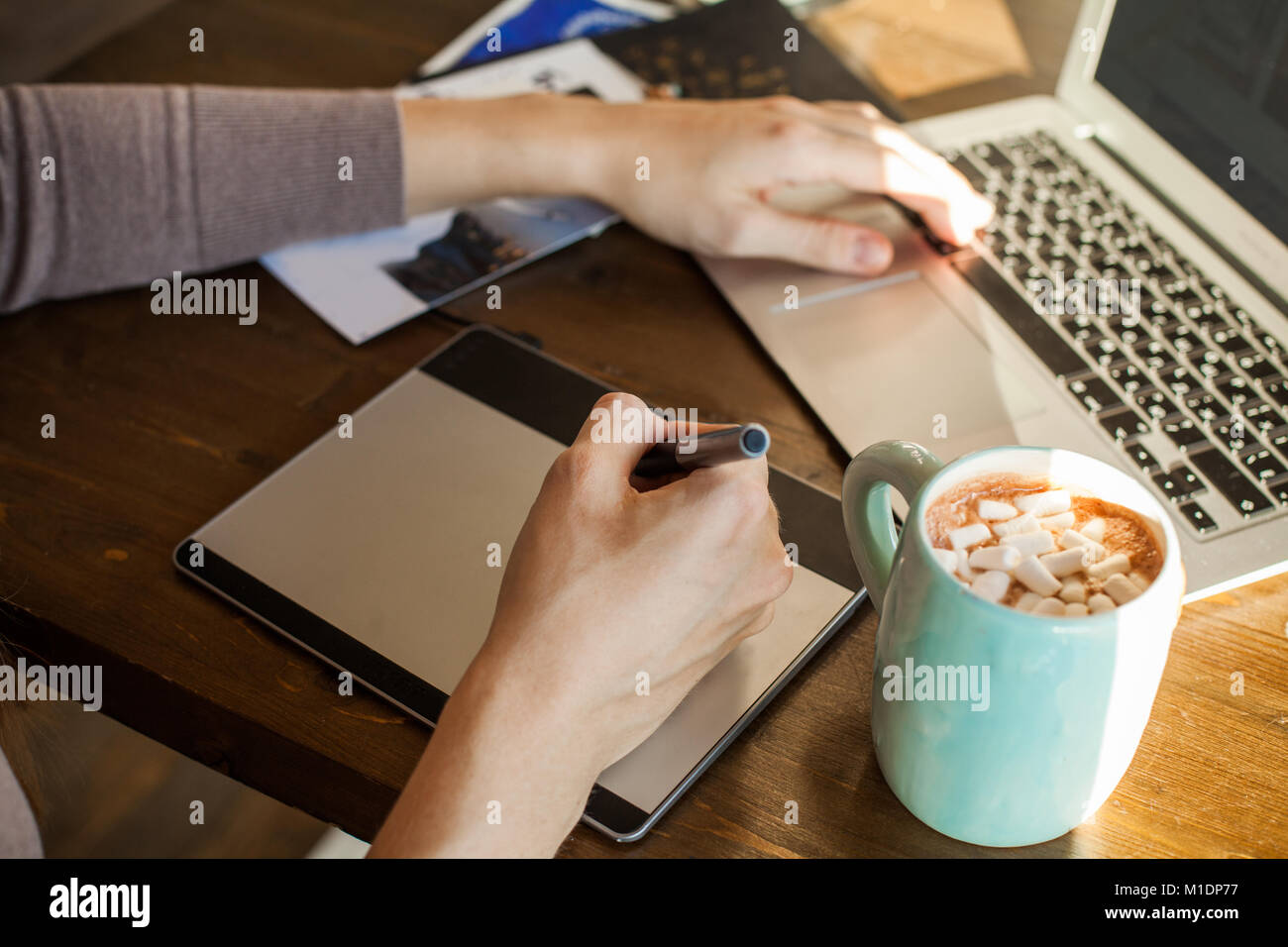 Designer con tavoletta grafica e il computer portatile presso l'ufficio domestico Foto Stock