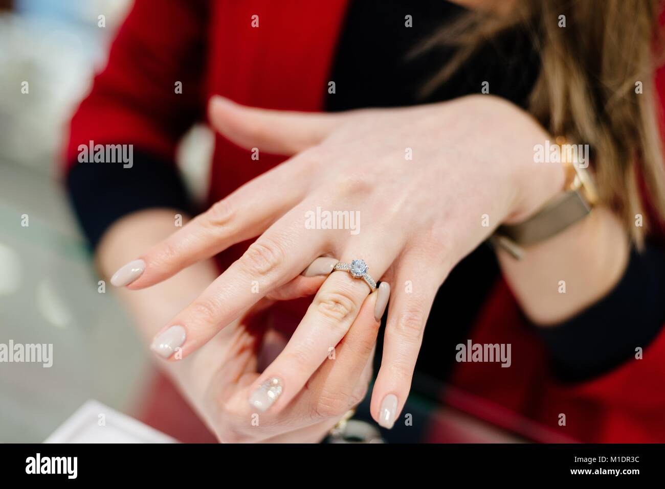 Venditore femmina nel lusso di un negozio gioielli presenta un anello. Acquisto di un anello di fidanzamento. Negozio gioielli. Donna gioielliere. Foto Stock