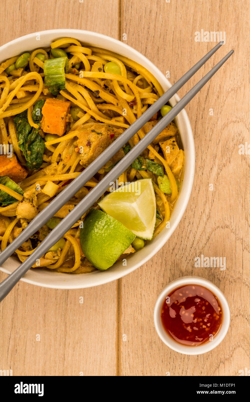 Giallo in stile Tailandese pollo al curry con pasta e patate dolci su di un legno chiaro dello sfondo della tabella Foto Stock