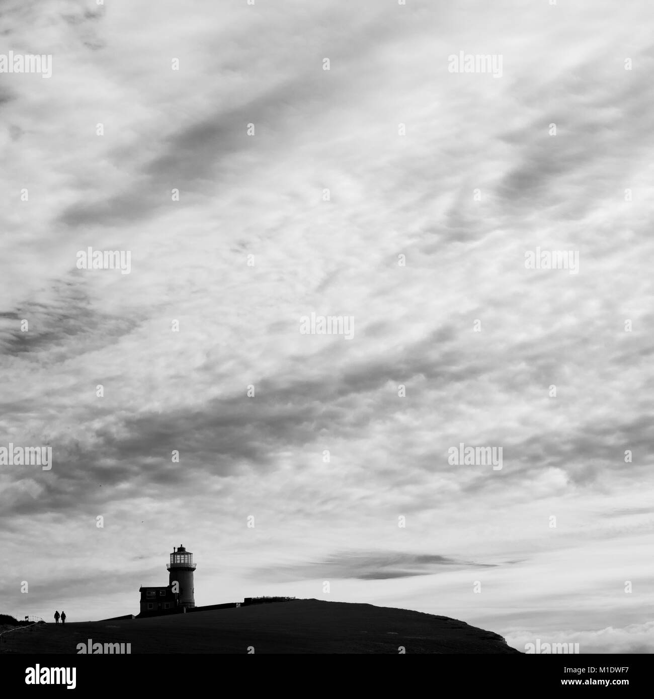 Giovane camminando accanto a Belle Tout faro, Beachy Head, East Sussex, stagliano big sky con le nuvole Foto Stock